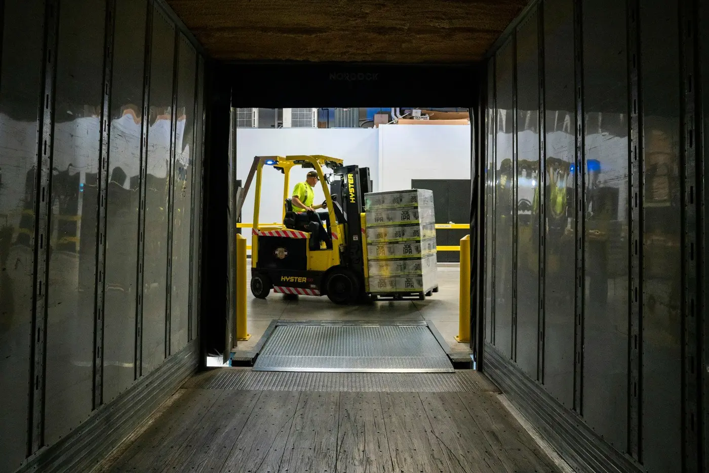 A forklift driver loads a wrapped pallet into a trailer