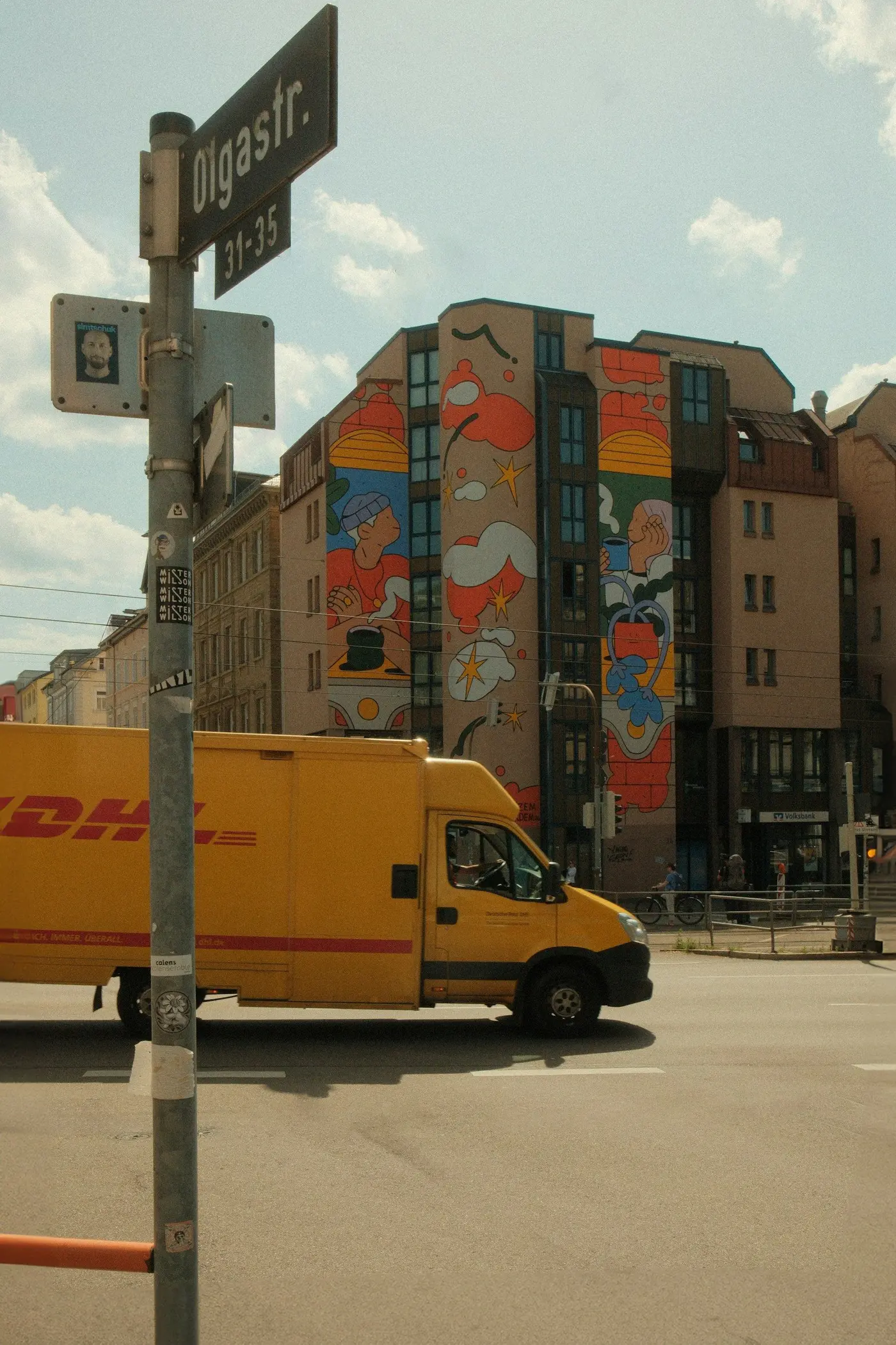 A yellow DHL van on a city street