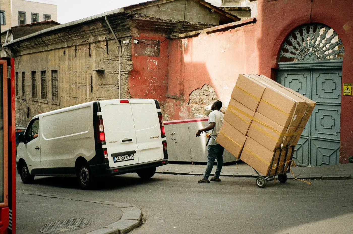 A driver wheels a stack of cartons from a white van to a door, for shipping from China to the United Kingdom