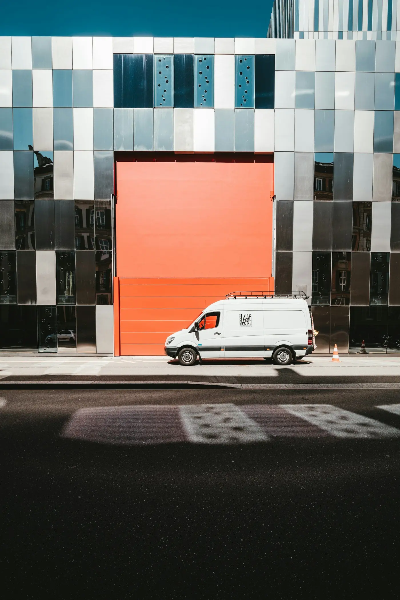 A white delivery van in front of an orange wall