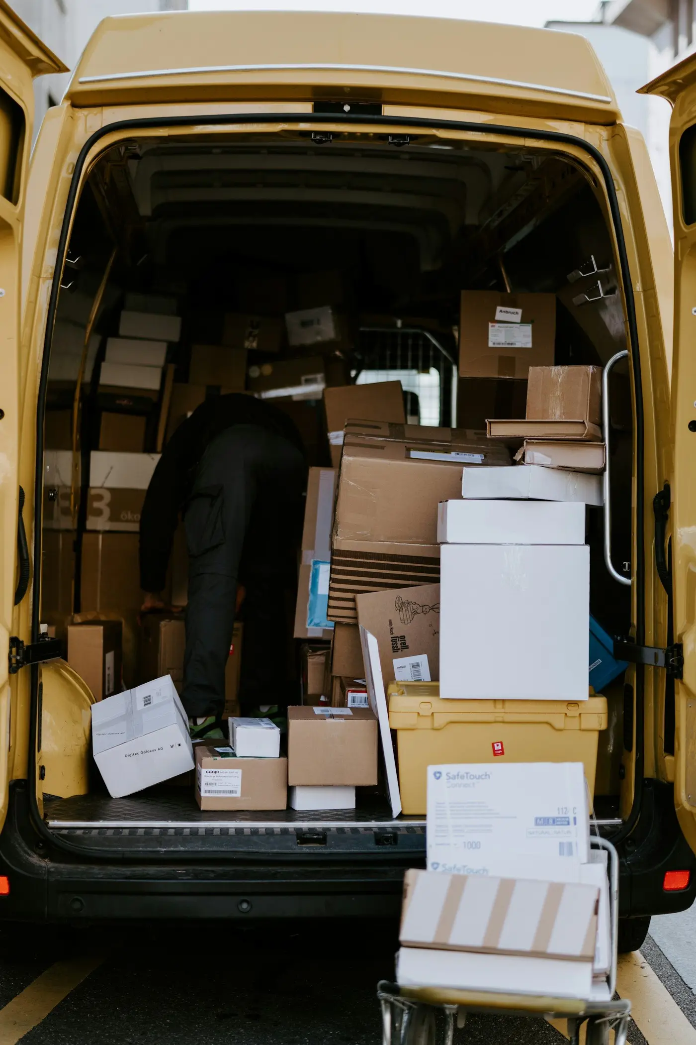 A driver loads cartons into a delivery van